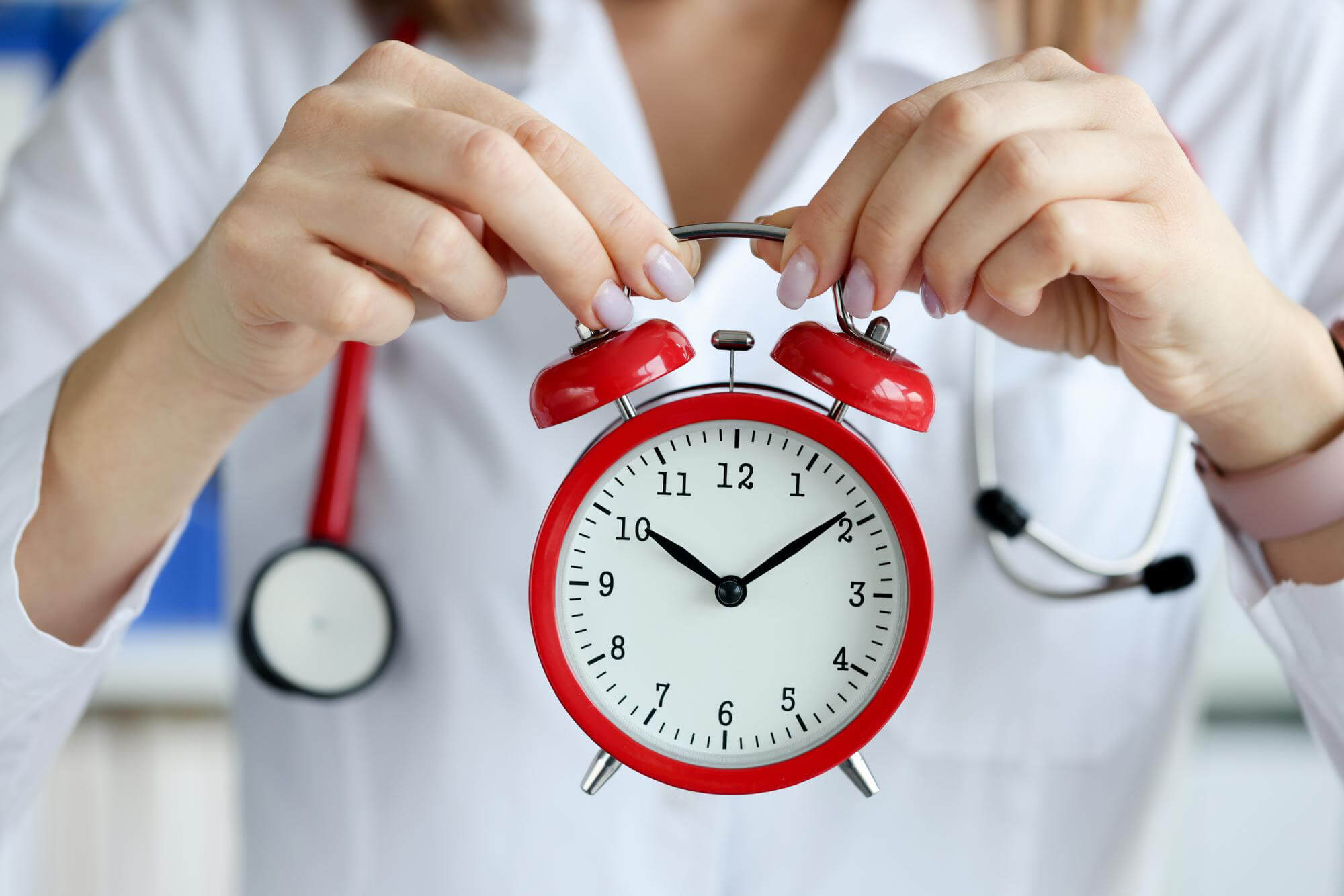 doctor-holding-red-alarm-clock-clinic-closeup (1)